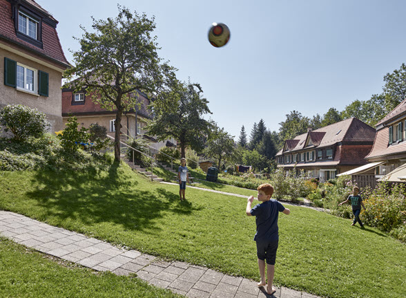 L’image montre des enfants jouant dans la cité Schoren de Saint-Gall. Cet ensemble d’habitation a été construit de 1911 à 1914 par la coopérative des cheminots.